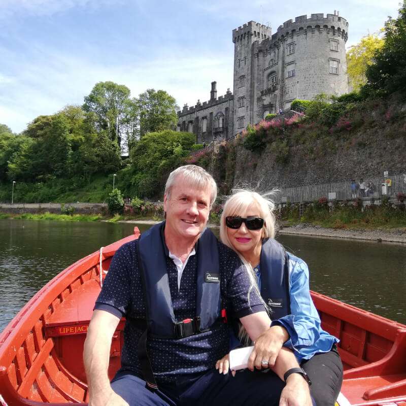 A couple on red tour boat in river Nore under Kilkenny Castle