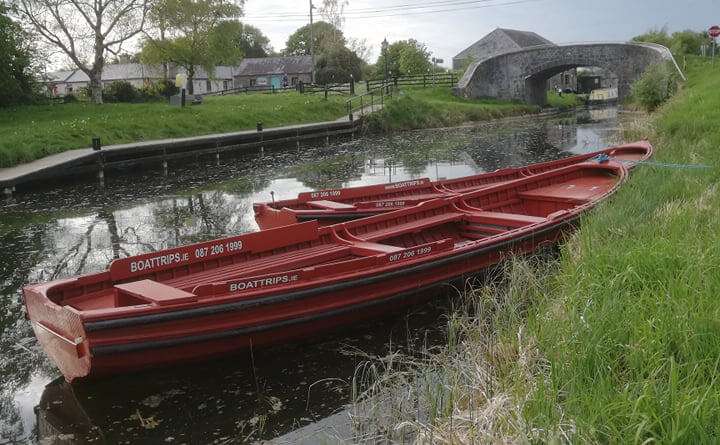 Two red Traditional Open-Boats moored on the Grand canal at Vicarstown. Stone bridge in the background