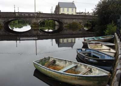 Small boats moored on river Barrow at Graiguecullen, Carlow, Ireland. Bridge in background.
