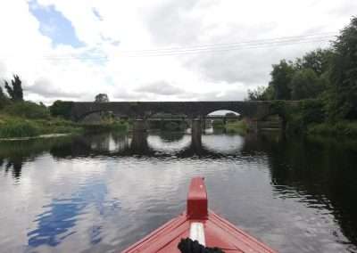 Bow of red boat approaching the Horse Bridge on river Barrow at Athy, Kildare, Ireland.