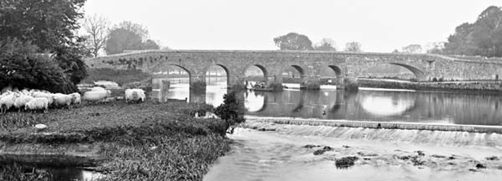 black and white picture of horsebridge with six arches. Weir on down stream side of bridge.